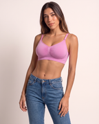 Model leaning in a relaxed pose in the Wireless Shaping Bra in candy pink