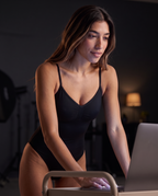 Model working at a computer in the One & Done Shaping Bodysuit in black