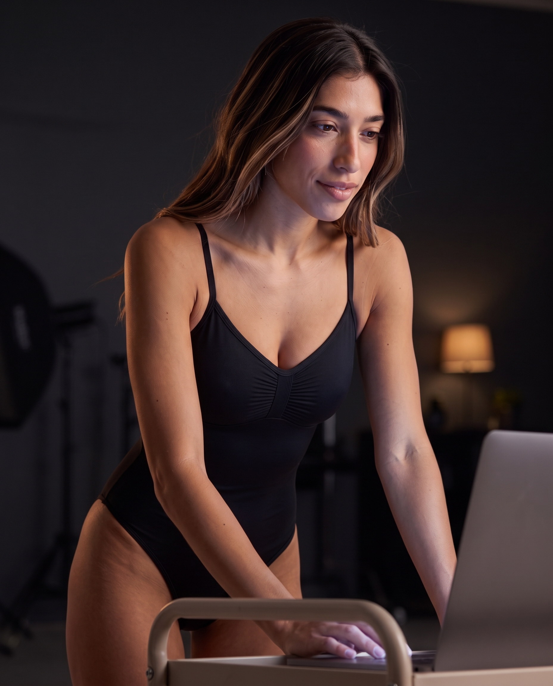 Model working at a computer in the One & Done Shaping Bodysuit in black