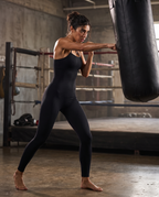 Model working a heavy bag in the Bra-Free Shaping Jumpsuit in Black.