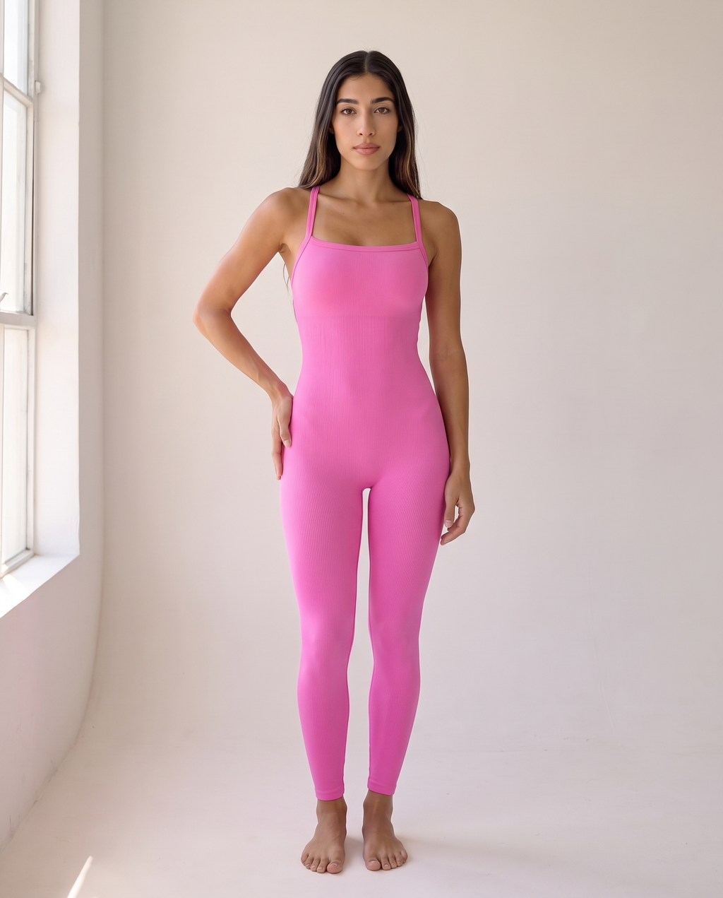 Editorial window-light portrait of the Bra-Free Shaping Jumpsuit in Blush Pink.