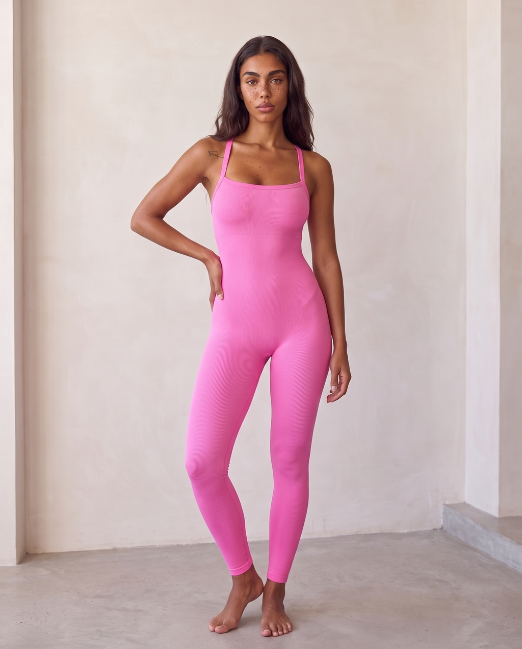 Editorial window-light portrait of the Bra-Free Shaping Jumpsuit in Blush Pink.