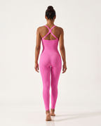 Model walking away in the Bra-Free Shaping Jumpsuit in Blush Pink, seen from behind.