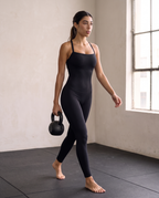 Model carrying a kettlebell in the Bra-Free Shaping Jumpsuit in Black.