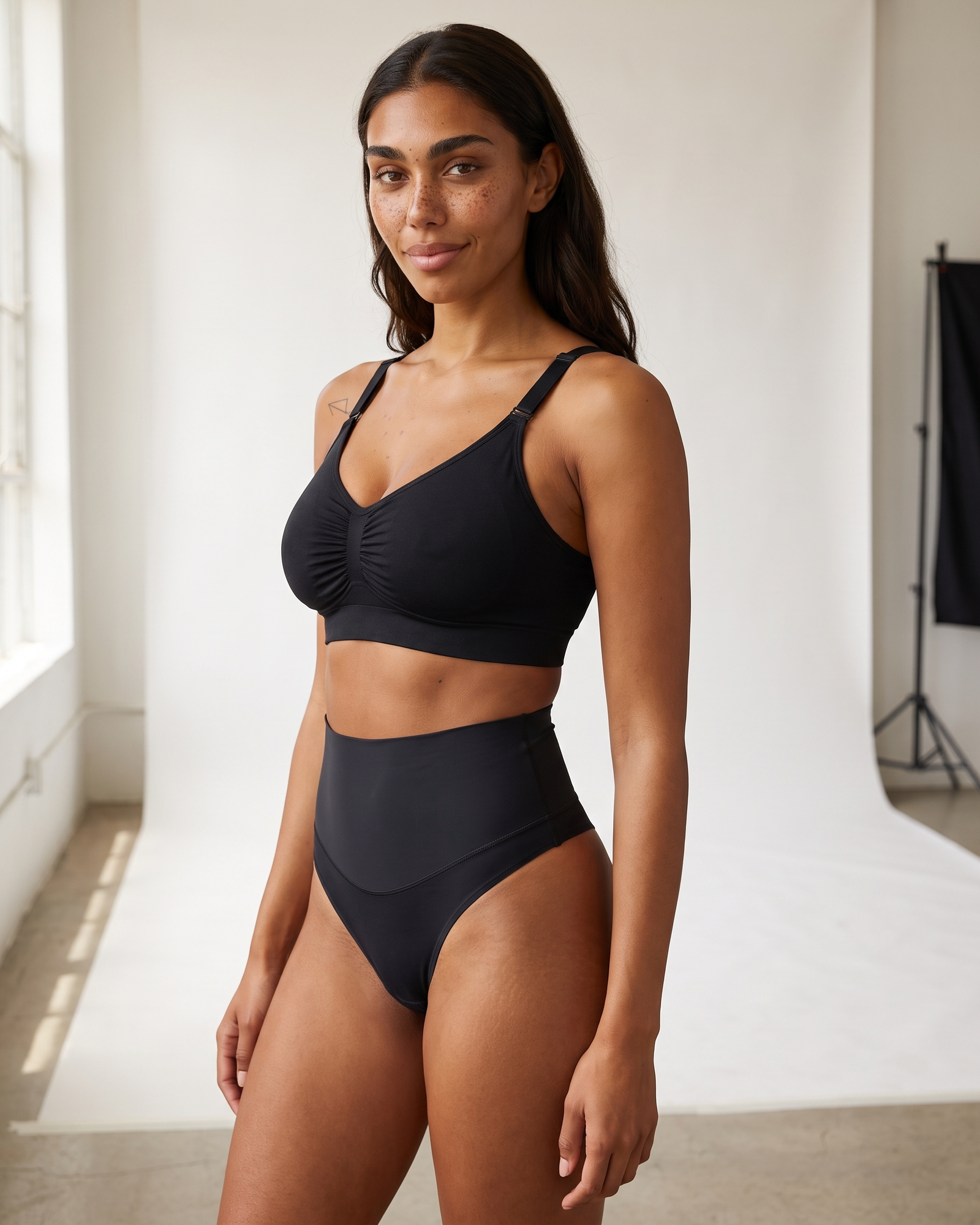 No-Show Tummy Control Thong in Black — three-quarter view, smiling.
