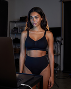 No-Show Tummy Control Thong in Black — in a dim laptop-lit room.